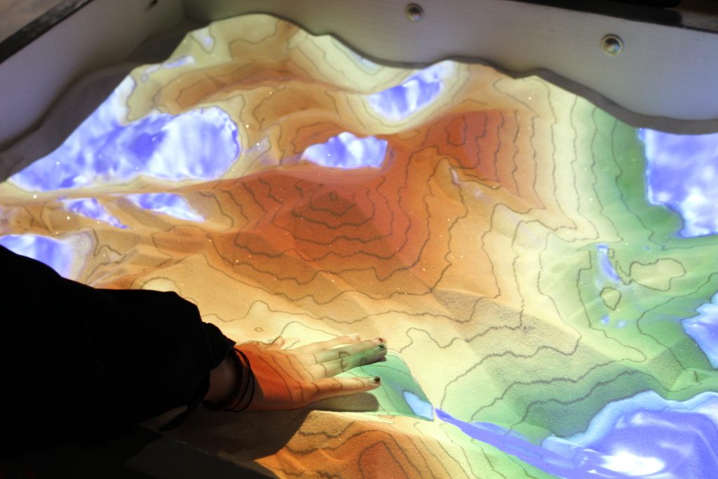 A close up photo of an AR sandbox displaying topography