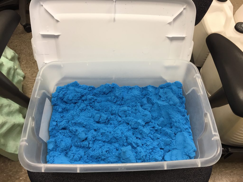 A plastic tub with blue sand inside